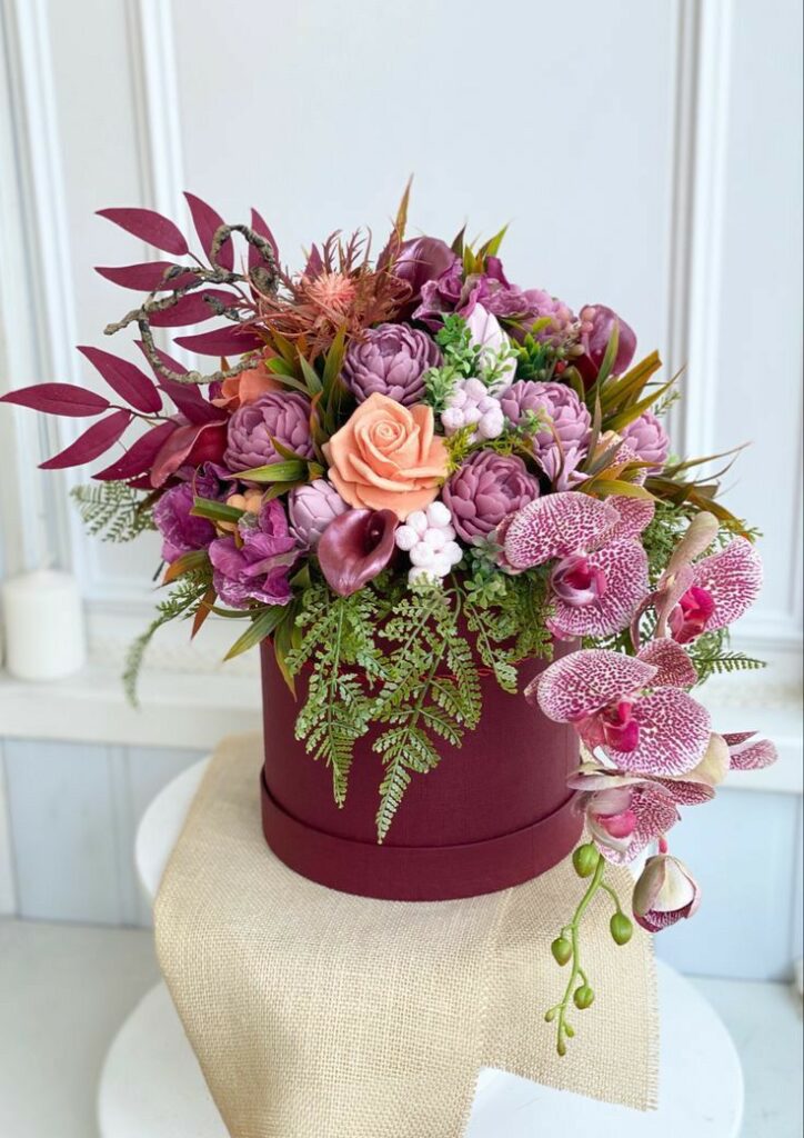 Ramo de rosas y orquídeas en una caja cilíndrica de color rojo