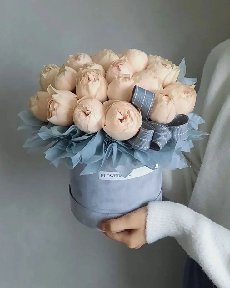 Caja azul que contiene ramo floral de rosas color crema