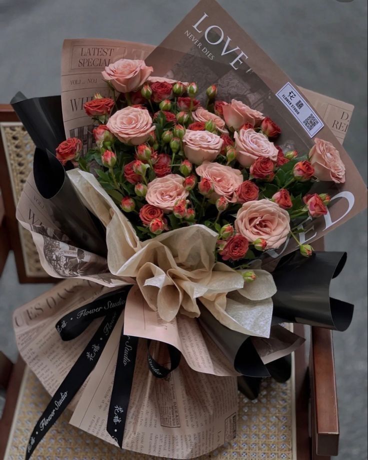 Ramo de flores rosas y rojas envueltos en papel decorado colocado sobre una silla